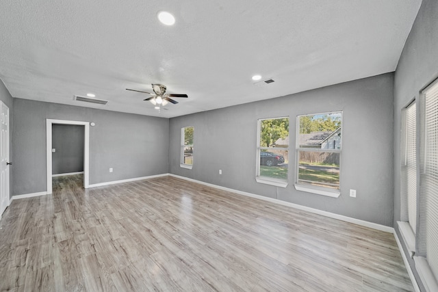 spare room with a textured ceiling, light wood-type flooring, and ceiling fan