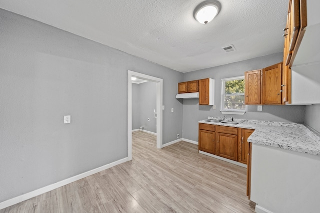 kitchen with sink, a textured ceiling, and light hardwood / wood-style floors