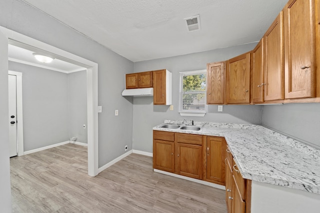 kitchen with light hardwood / wood-style flooring, a textured ceiling, and sink