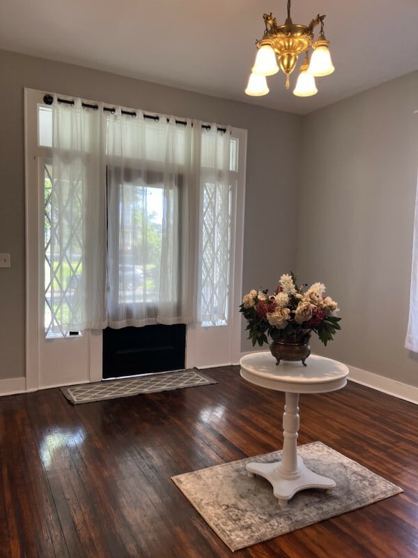 entrance foyer featuring dark hardwood / wood-style floors, a chandelier, and a healthy amount of sunlight