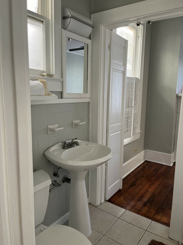 bathroom with tile walls, hardwood / wood-style floors, and toilet