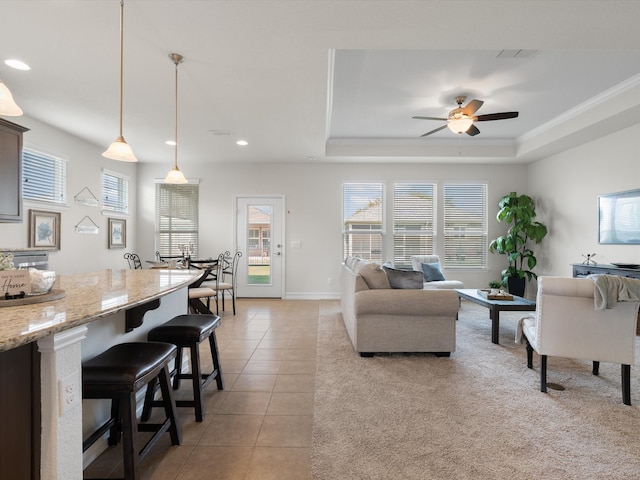 tiled living room with a tray ceiling and ceiling fan