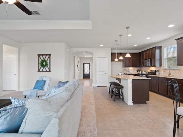 living room featuring ceiling fan, ornamental molding, sink, and light tile patterned floors