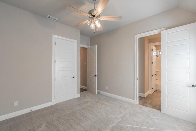 unfurnished bedroom featuring light carpet, ceiling fan, and ensuite bathroom