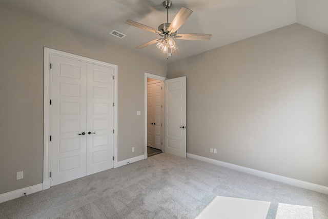 unfurnished bedroom featuring ceiling fan, light colored carpet, lofted ceiling, and a closet