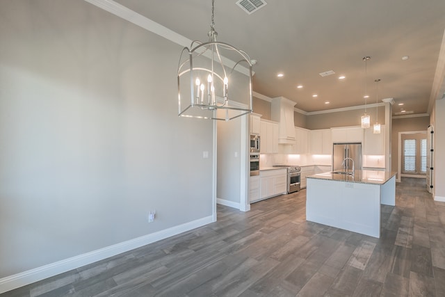 kitchen with a kitchen island with sink, dark hardwood / wood-style floors, stainless steel appliances, hanging light fixtures, and white cabinetry