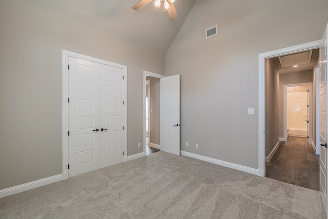 unfurnished bedroom with a closet, high vaulted ceiling, dark carpet, and ceiling fan