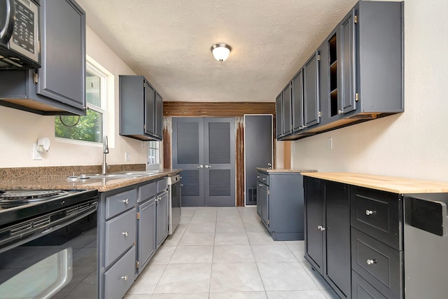 kitchen with a textured ceiling, stainless steel appliances, sink, and light tile patterned floors