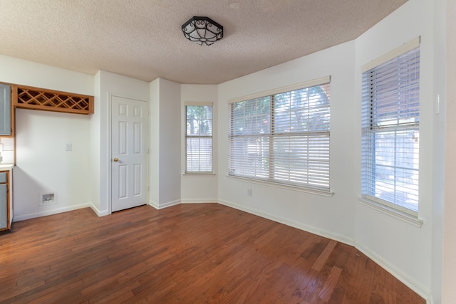 unfurnished dining area featuring wood-type flooring, a textured ceiling, and plenty of natural light