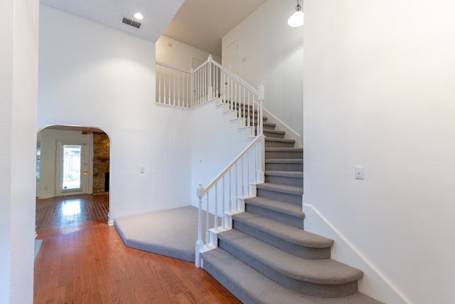 stairway featuring a towering ceiling and hardwood / wood-style floors