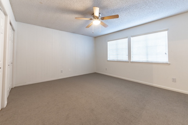 spare room with ceiling fan, a textured ceiling, and dark carpet