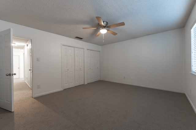 unfurnished bedroom with multiple windows, ceiling fan, dark carpet, and a textured ceiling