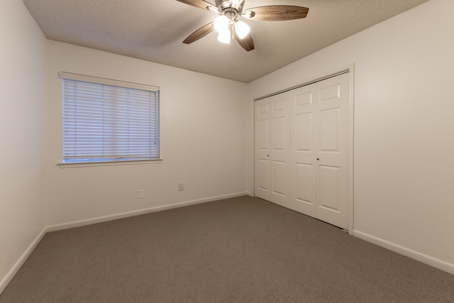 unfurnished bedroom with ceiling fan, a textured ceiling, a closet, and dark carpet