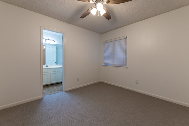 unfurnished bedroom with dark colored carpet, ceiling fan, connected bathroom, and a textured ceiling