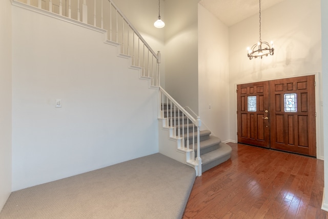 foyer with a towering ceiling, hardwood / wood-style floors, and a chandelier