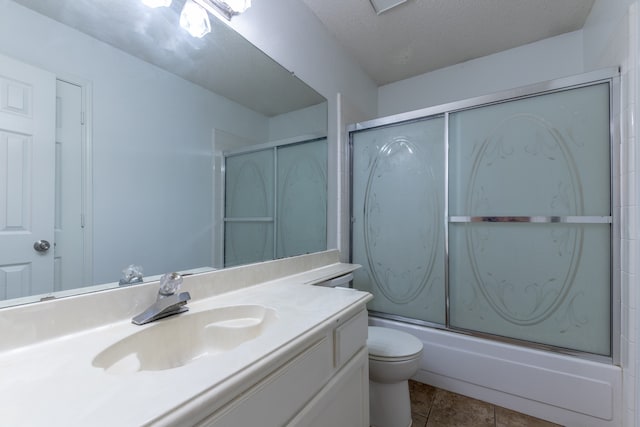 full bathroom featuring toilet, tile patterned floors, shower / bath combination with glass door, vanity, and a textured ceiling