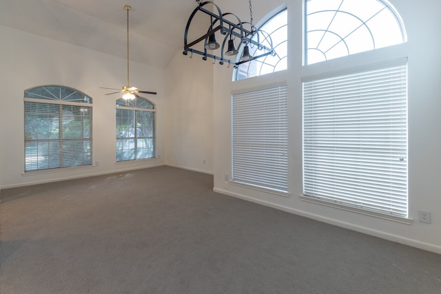 carpeted spare room with ceiling fan with notable chandelier and high vaulted ceiling