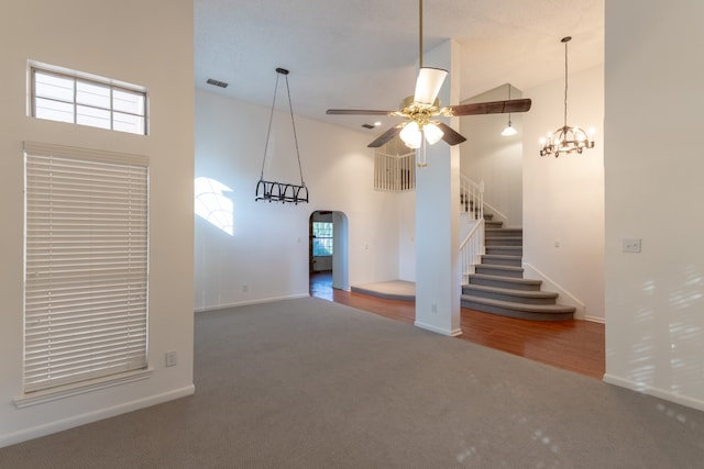 unfurnished living room with a high ceiling, ceiling fan, and carpet floors