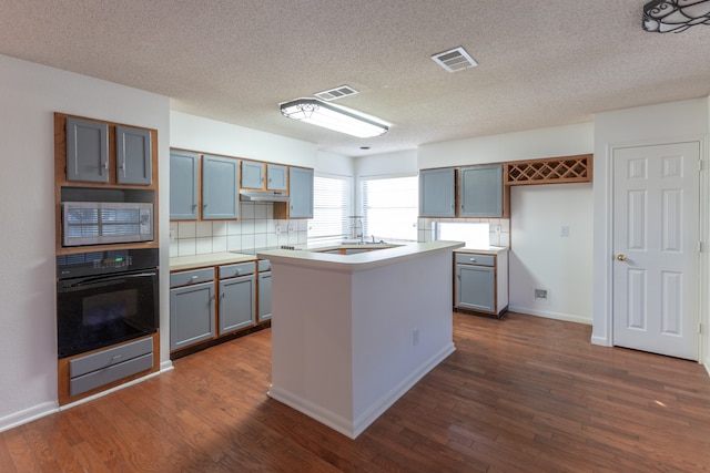 kitchen with backsplash, oven, stainless steel microwave, dark hardwood / wood-style floors, and a center island