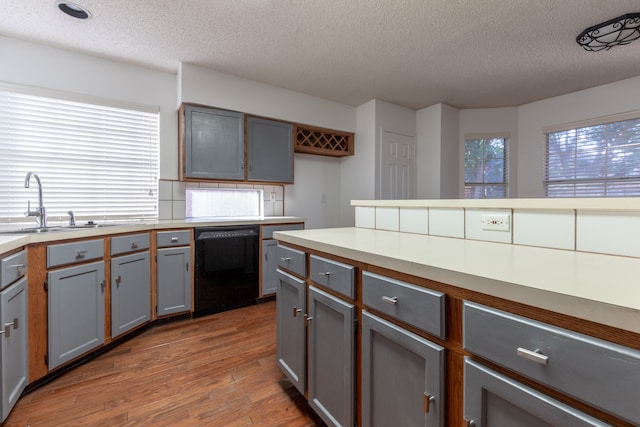 kitchen featuring dark hardwood / wood-style floors, black dishwasher, gray cabinets, and a textured ceiling