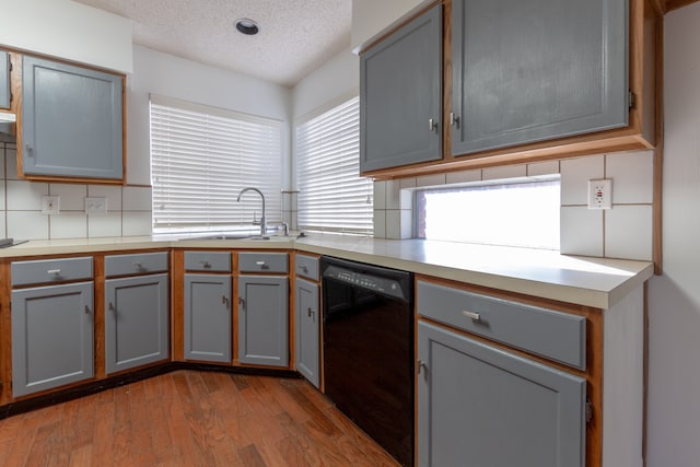 kitchen with a textured ceiling, gray cabinetry, sink, and dishwasher