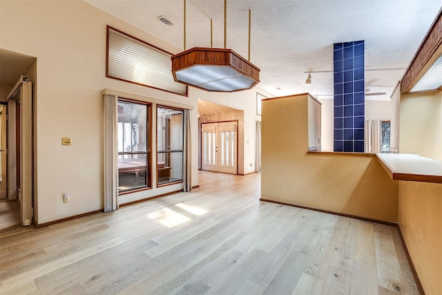 interior space with a towering ceiling, light hardwood / wood-style floors, and a textured ceiling