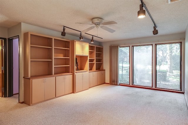 unfurnished living room featuring ceiling fan, track lighting, a textured ceiling, and light carpet