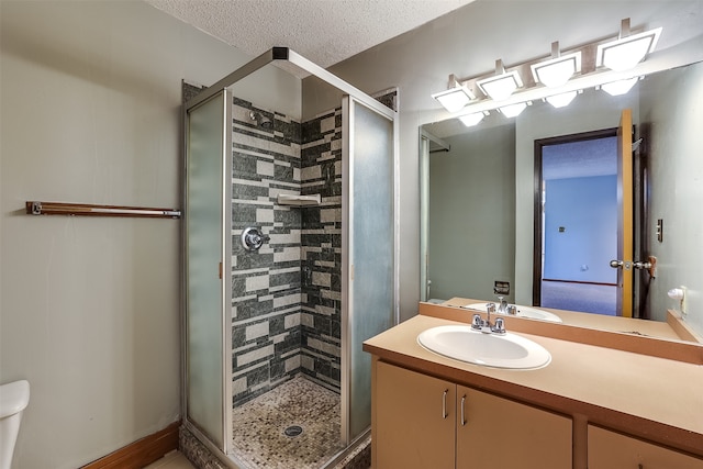 bathroom with a textured ceiling, a shower with shower door, vanity, and toilet