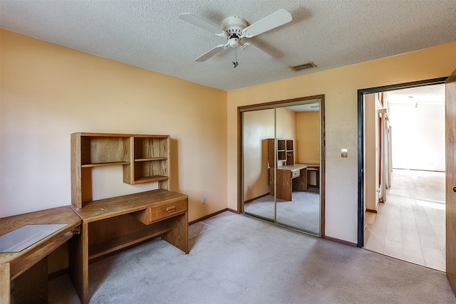 carpeted office space with ceiling fan and a textured ceiling