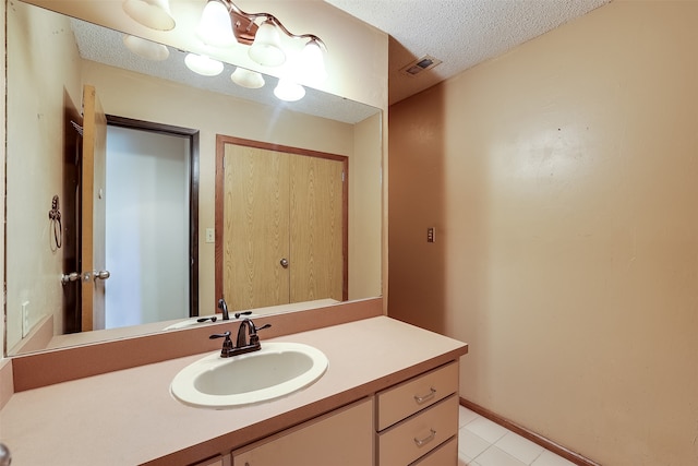 bathroom with vanity, a textured ceiling, and tile patterned floors