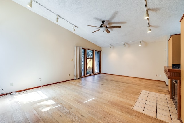 unfurnished living room with ceiling fan, a textured ceiling, lofted ceiling, and light hardwood / wood-style floors