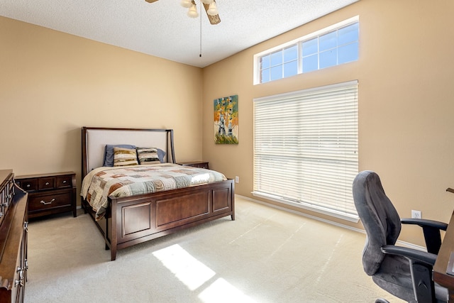 bedroom featuring light carpet, a textured ceiling, and ceiling fan