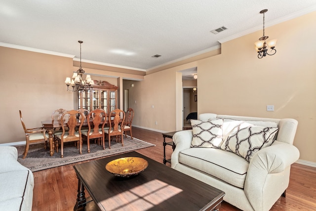 living room featuring crown molding, a chandelier, hardwood / wood-style flooring, and a textured ceiling