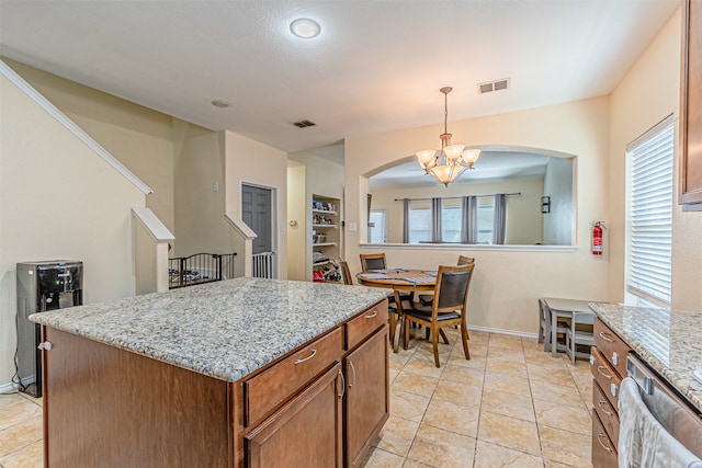 kitchen featuring hanging light fixtures, light tile patterned floors, a kitchen island, a chandelier, and light stone countertops