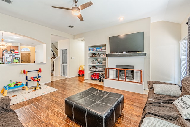 living room with ceiling fan, built in shelves, and wood-type flooring