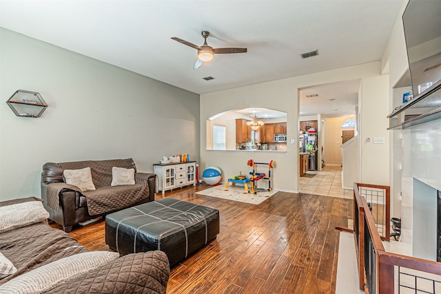 living room featuring ceiling fan with notable chandelier and light hardwood / wood-style floors