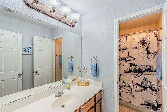 bathroom with a textured ceiling, tile patterned floors, vanity, and a shower with curtain