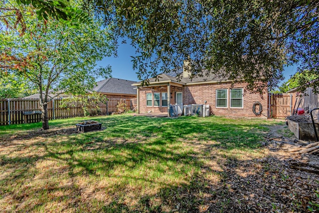 rear view of property with a lawn and an outdoor fire pit