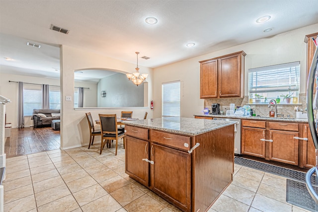 kitchen featuring decorative light fixtures, a notable chandelier, sink, dishwasher, and a center island