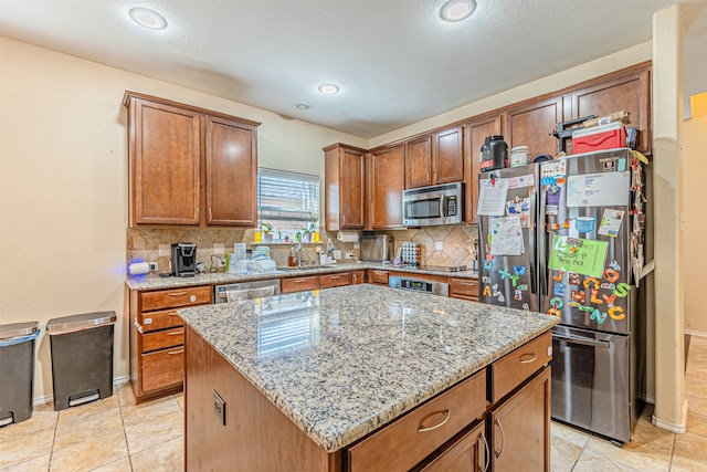 kitchen featuring light stone counters, stainless steel appliances, tasteful backsplash, and a center island