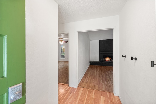 hallway with light wood-type flooring and a textured ceiling