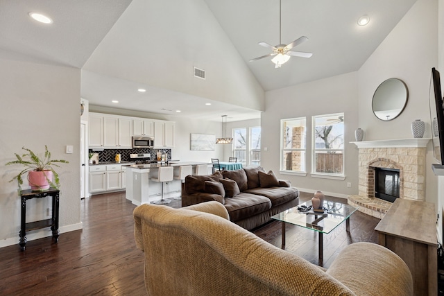 living room featuring high vaulted ceiling, a fireplace, ceiling fan, and dark hardwood / wood-style floors