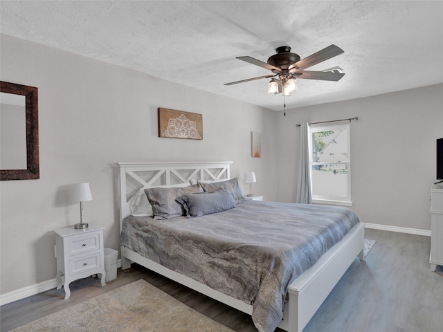 bedroom featuring ceiling fan, hardwood / wood-style floors, and a textured ceiling