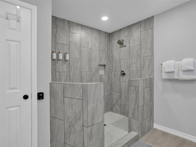 bathroom with hardwood / wood-style floors and a tile shower