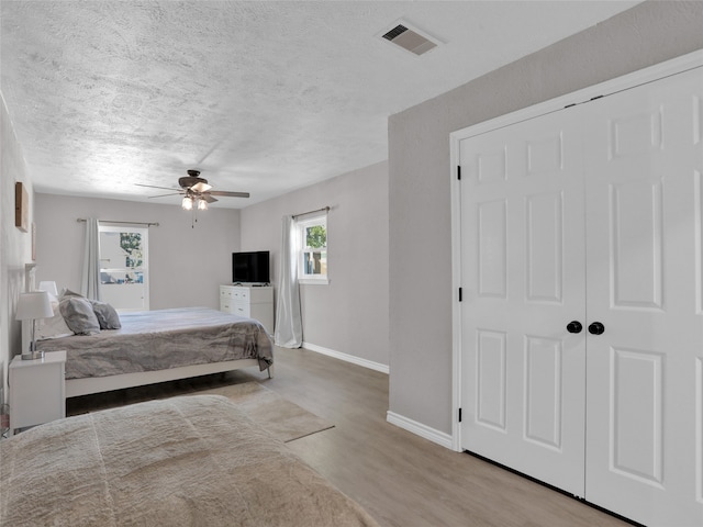 bedroom with light hardwood / wood-style flooring, a textured ceiling, and ceiling fan