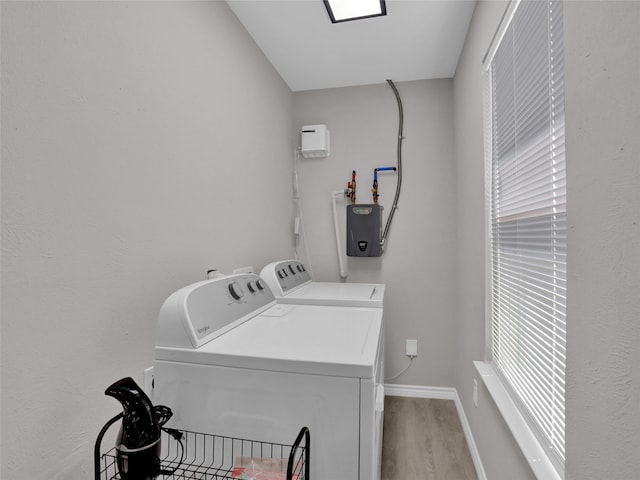 clothes washing area with light hardwood / wood-style floors and washer and dryer