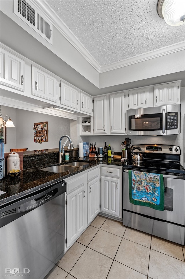 kitchen featuring sink, stainless steel appliances, ornamental molding, white cabinets, and a textured ceiling