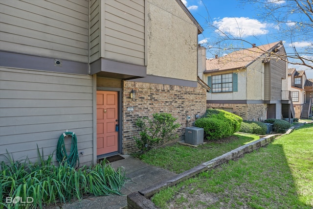 property entrance with cooling unit and a lawn