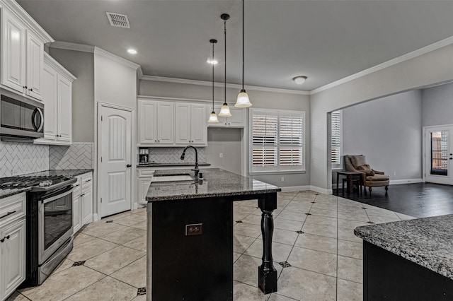 kitchen featuring white cabinets, stainless steel appliances, a kitchen island with sink, and sink