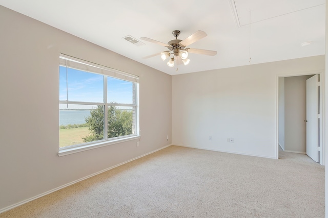 unfurnished room featuring a water view, a healthy amount of sunlight, ceiling fan, and light carpet